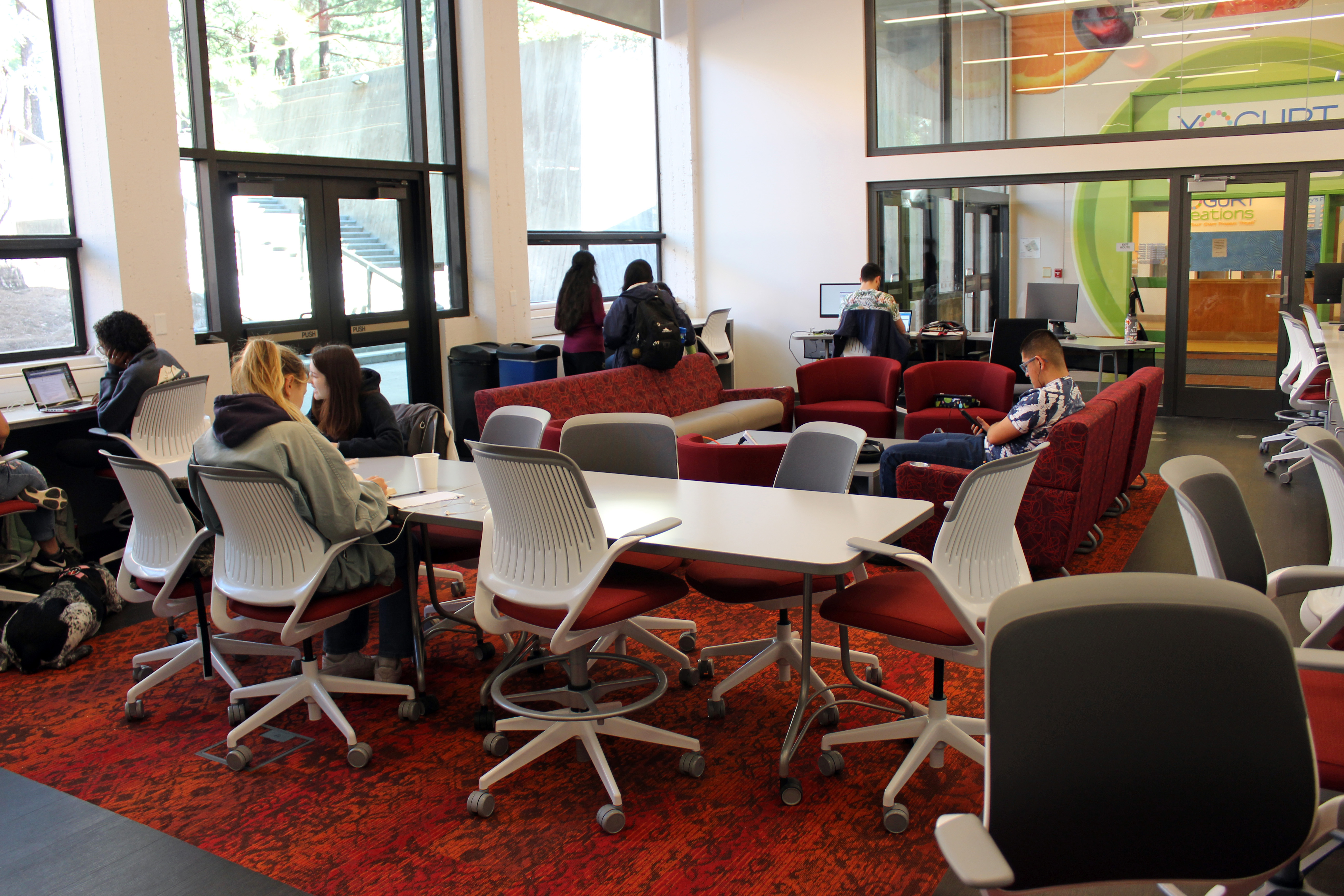 Students sit while studying and on their phones in red lounge chairs in the new MultiCultural Center